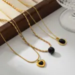 LIVKE’s gold-plated agate heart necklace styled with black silk dress for timeless minimalist elegance