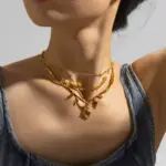 Maillard-Style Tiger Eye Necklace – 18K Gold-Plated 5 LIVKE’s oval tiger eye necklace with 18K gold-plated chain, styled with black sweater for minimalist elegance.