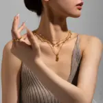 18K Gold Circular Lock Necklace 3 Close-up of LIVKE’s electroplated 18K gold brass zircon stone necklace with a round lock clasp, styled over a chic neckline.