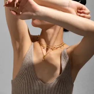 Close-up of LIVKE’s electroplated 18K gold brass zircon stone necklace with a round lock clasp, styled over a chic neckline.