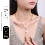 Summer Wave Necklace 4 LIVKE’s gold summer wave necklace with shell and zirconia pendant, styled with a straw hat for beachside elegance.