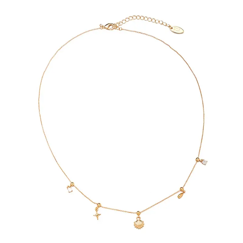 LIVKE’s gold summer wave necklace with shell and zirconia pendant, styled with a straw hat for beachside elegance.