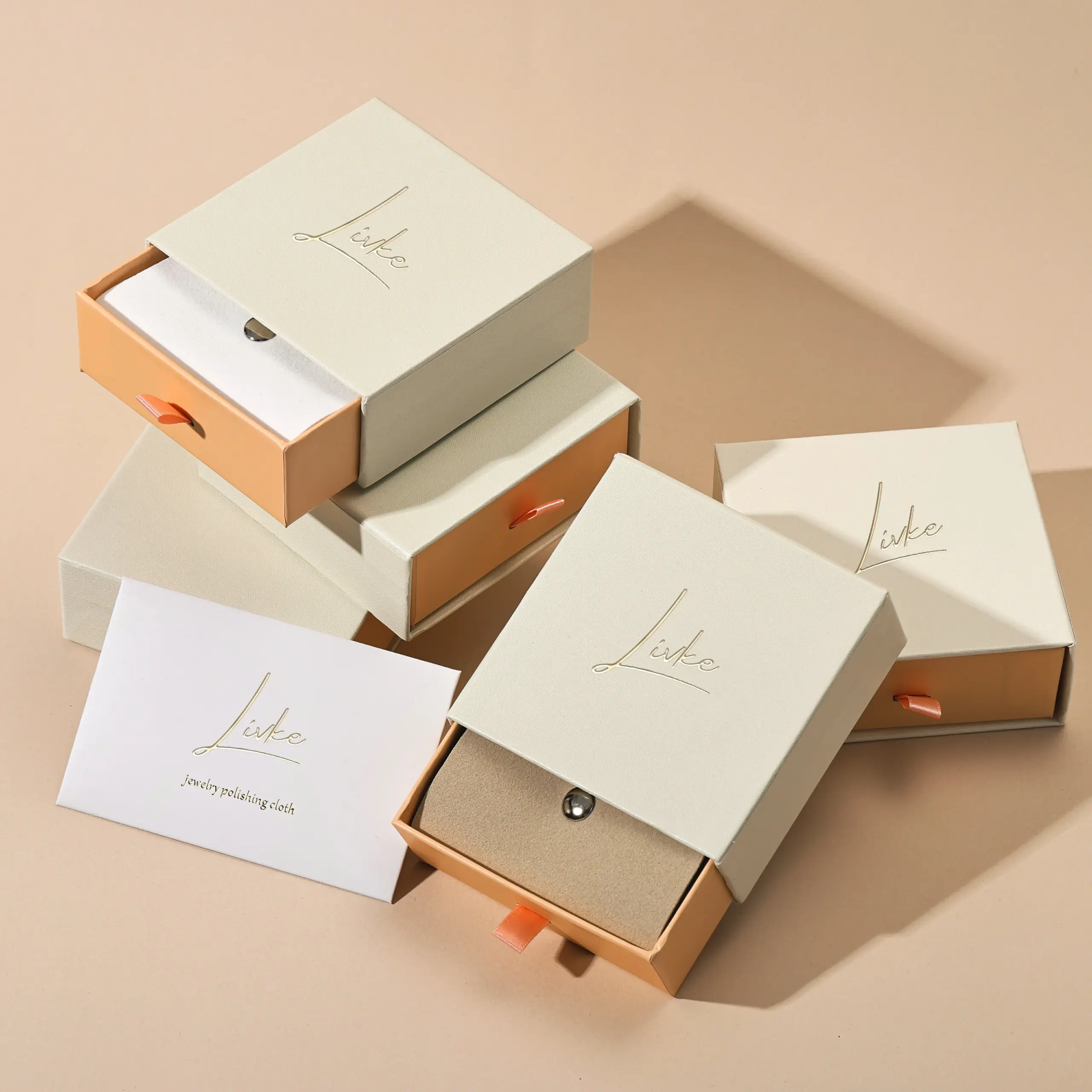 Beige drawer box open with polishing cloth, necklace and ring on velvet background