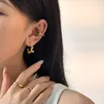 18K Gold Plated Vine Earrings 2 Woman wearing LIVKE gold vine earrings with green gemstones at outdoor garden party, showcasing organic luxury jewelry