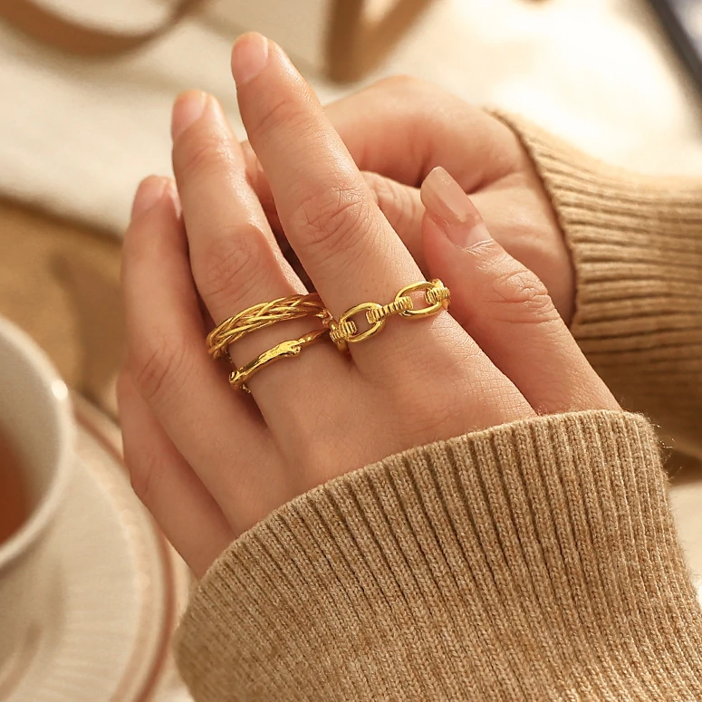 Stacked LIVKE braided and chain rings on hand with bohemian embroidery sleeve, showcasing boho-chic layering.