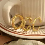 Braided Gold Rings – Geometric Hollow Design 7 Stacked LIVKE braided and chain rings on hand with bohemian embroidery sleeve, showcasing boho-chic layering.