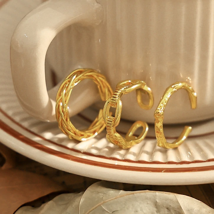 Stacked LIVKE braided and chain rings on hand with bohemian embroidery sleeve, showcasing boho-chic layering.