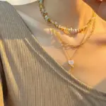 Woman wearing LIVKE cat and shell necklace walking with cat on sunset beach, symbolizing pet love and coastal aesthetic jewelry