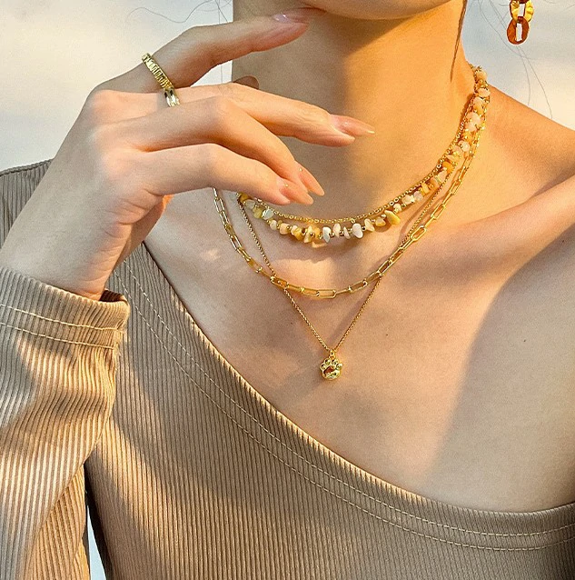 Woman wearing LIVKE cat and shell necklace walking with cat on sunset beach, symbolizing pet love and coastal aesthetic jewelry