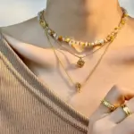 Woman wearing LIVKE cat and shell necklace walking with cat on sunset beach, symbolizing pet love and coastal aesthetic jewelry