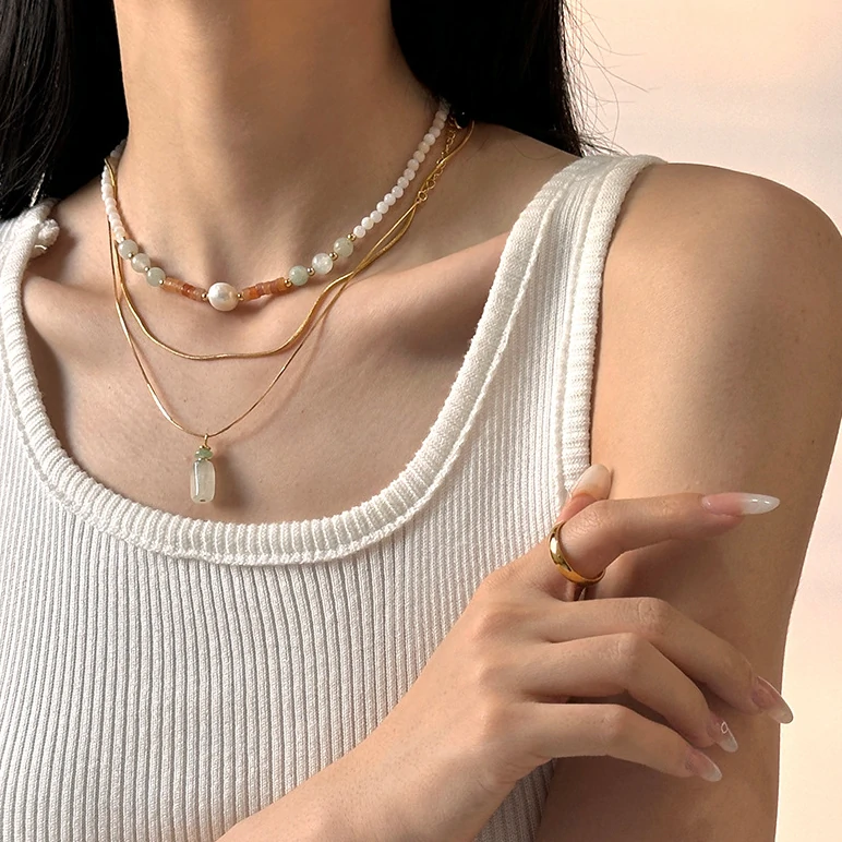 Woman wearing LIVKE green aventurine and white jade necklace with cashmere sweater, showcasing minimalist jewelry for urban elegance