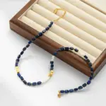 Lapis Lazuli & Gold Beaded Necklace 5 Woman wearing LIVKE lapis lazuli and gold beaded necklace with tailored black dress, showcasing mysterious yet elegant office-to-event jewelry