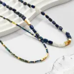 Lapis Lazuli & Gold Beaded Necklace 4 Woman wearing LIVKE lapis lazuli and gold beaded necklace with tailored black dress, showcasing mysterious yet elegant office-to-event jewelry