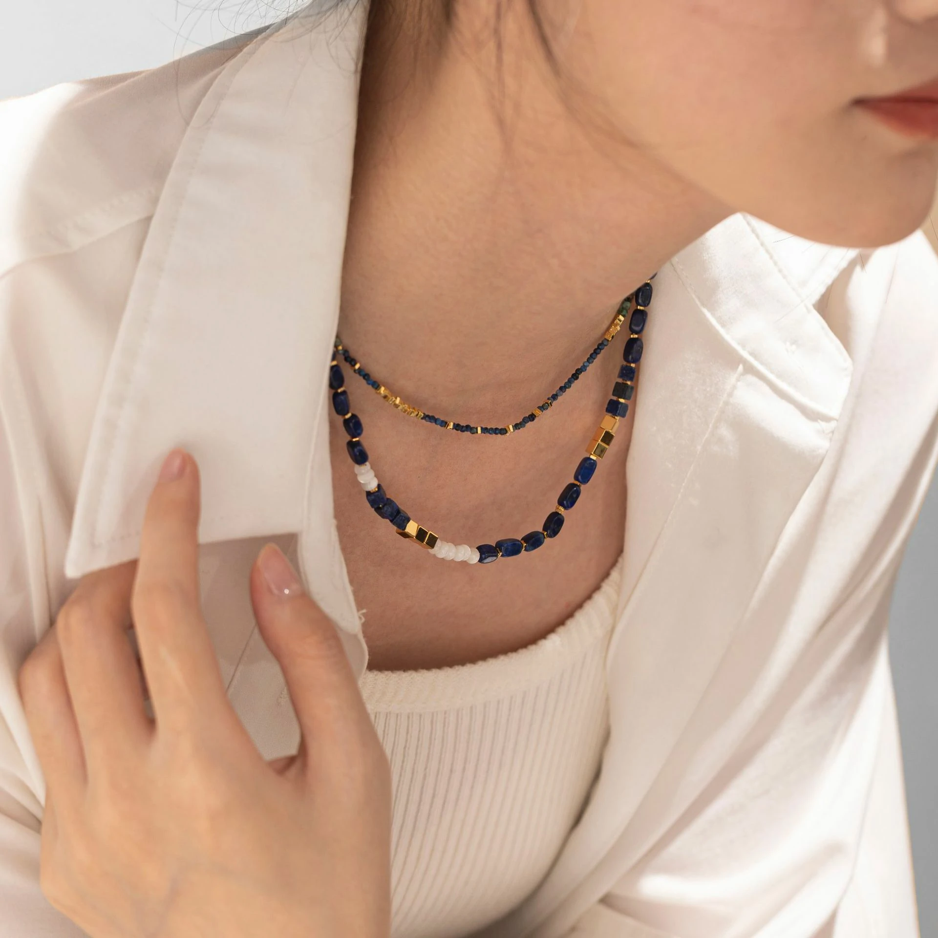 Woman wearing LIVKE lapis lazuli and gold beaded necklace with tailored black dress, showcasing mysterious yet elegant office-to-event jewelry