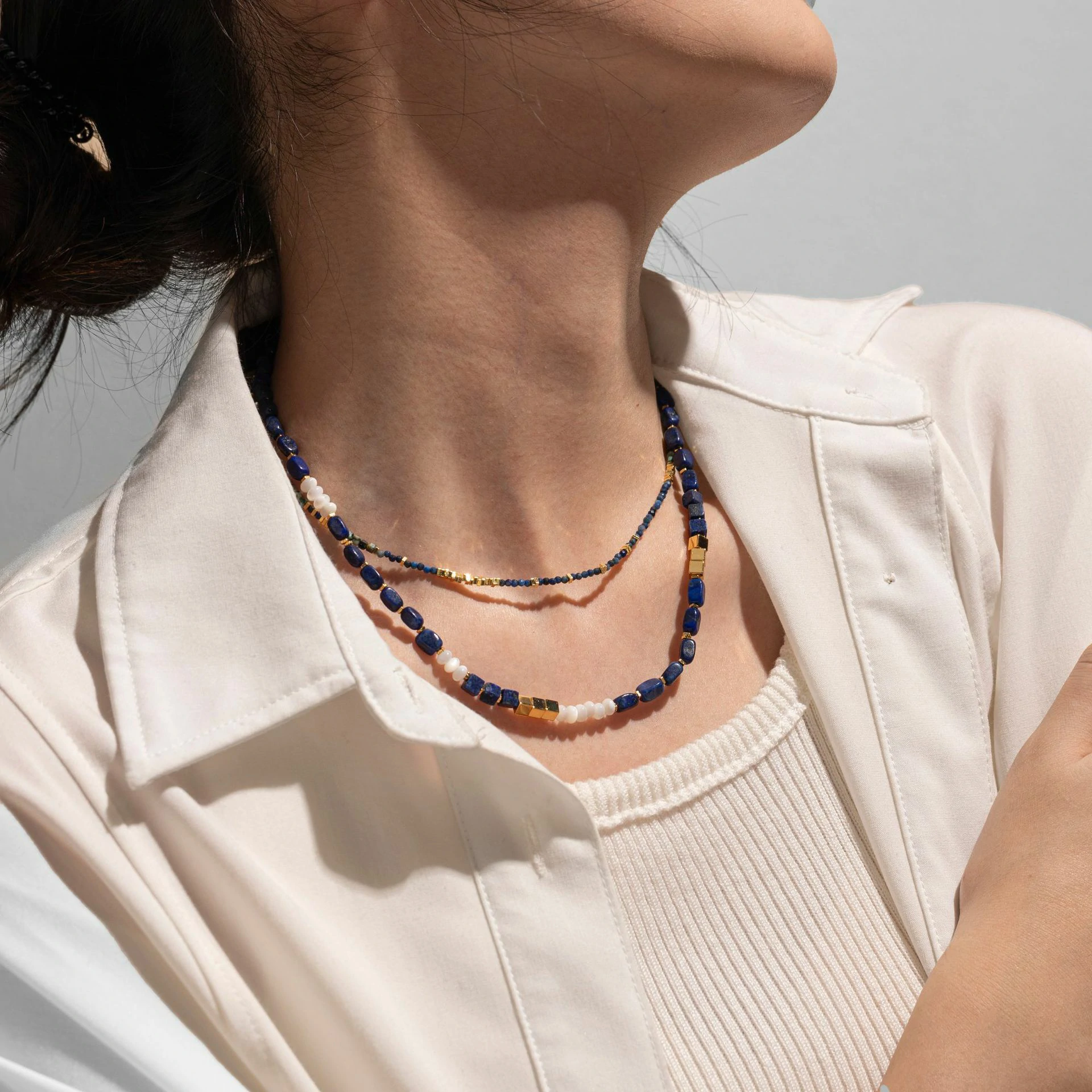 Woman wearing LIVKE lapis lazuli and gold beaded necklace with tailored black dress, showcasing mysterious yet elegant office-to-event jewelry