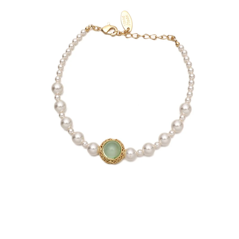 Stylist mixing LIVKE gold chain modules with baroque pearls on antique velvet tray in Paris concept store