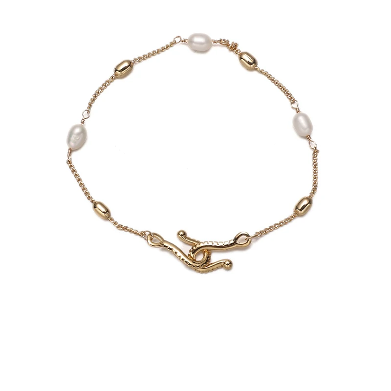 Stylist mixing LIVKE gold chain modules with baroque pearls on antique velvet tray in Paris concept store