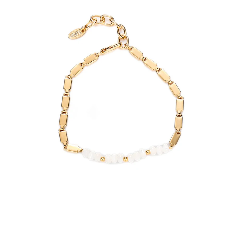 Stylist mixing LIVKE gold chain modules with baroque pearls on antique velvet tray in Paris concept store