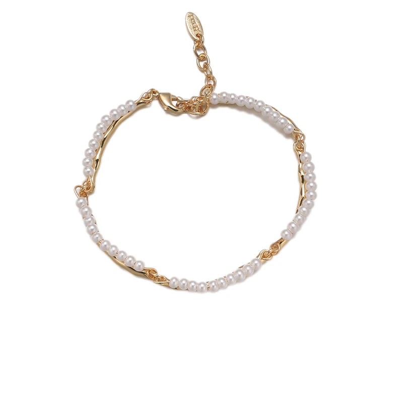 Stylist mixing LIVKE gold chain modules with baroque pearls on antique velvet tray in Paris concept store