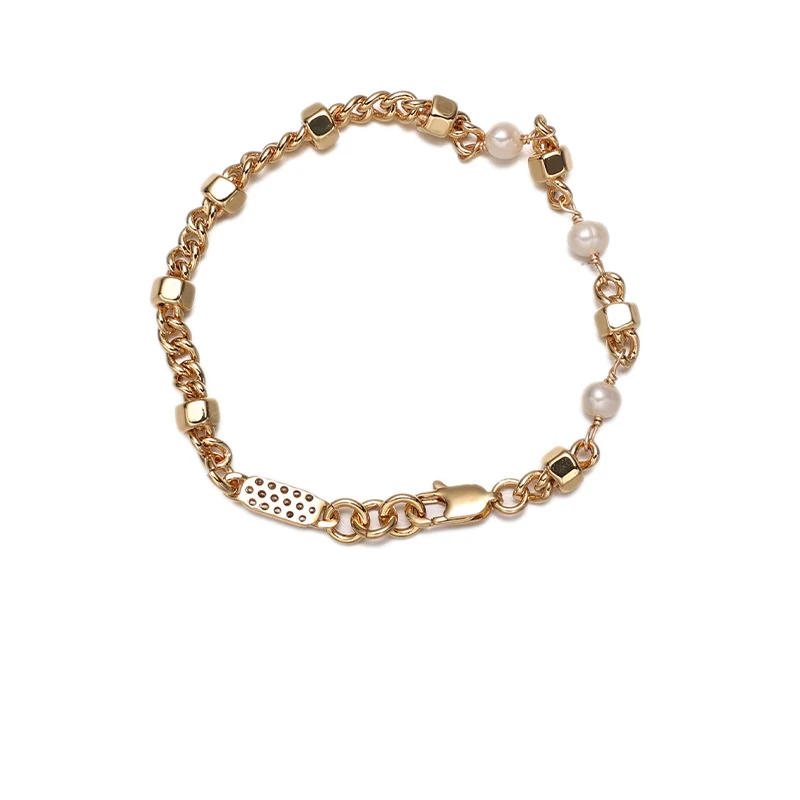 Stylist mixing LIVKE gold chain modules with baroque pearls on antique velvet tray in Paris concept store