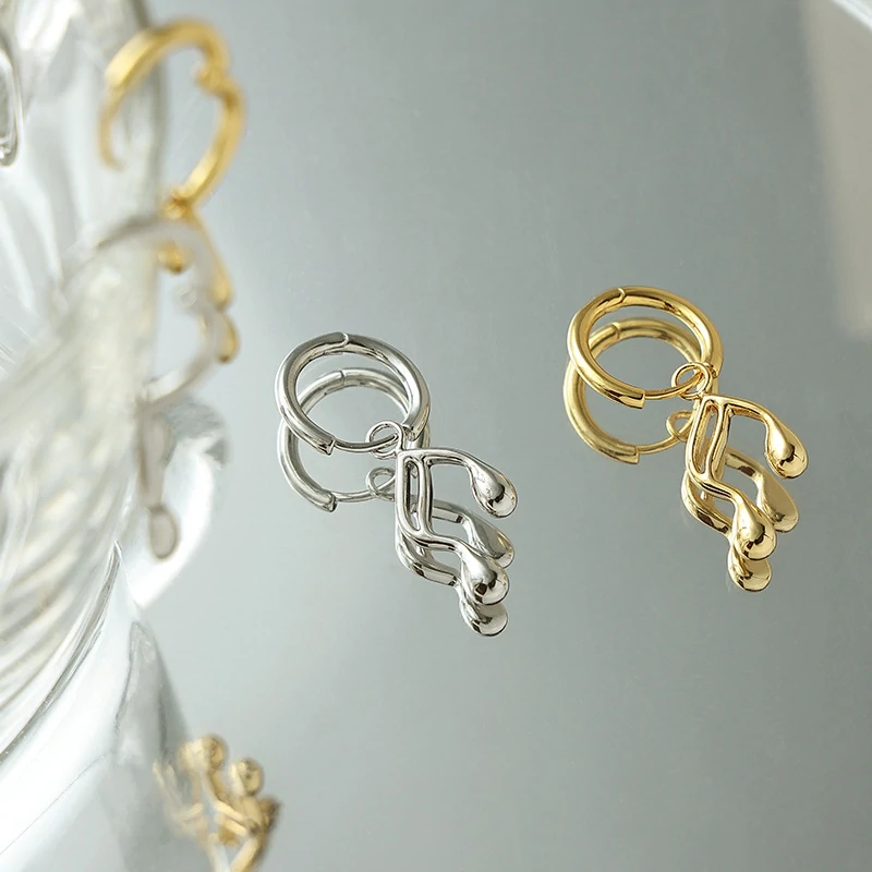 Gold note-shaped ear cuff on model's ear with sheet music background