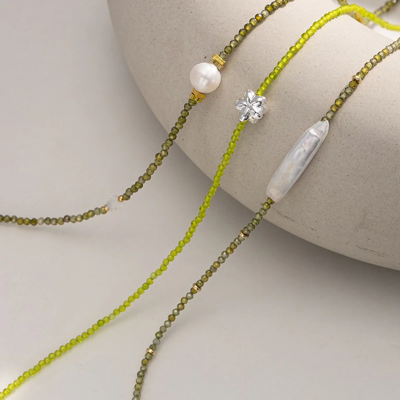 Woman wearing LIVKE pearl and green beaded necklace with silk blouse, showcasing minimalist jewelry for work and evening events