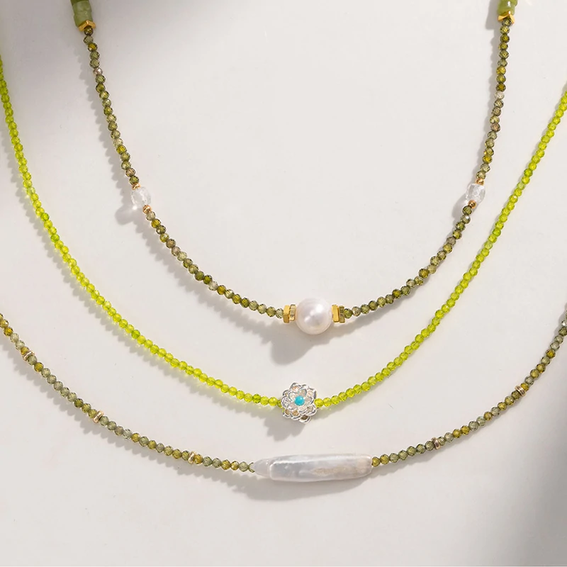 Woman wearing LIVKE pearl and green beaded necklace with silk blouse, showcasing minimalist jewelry for work and evening events