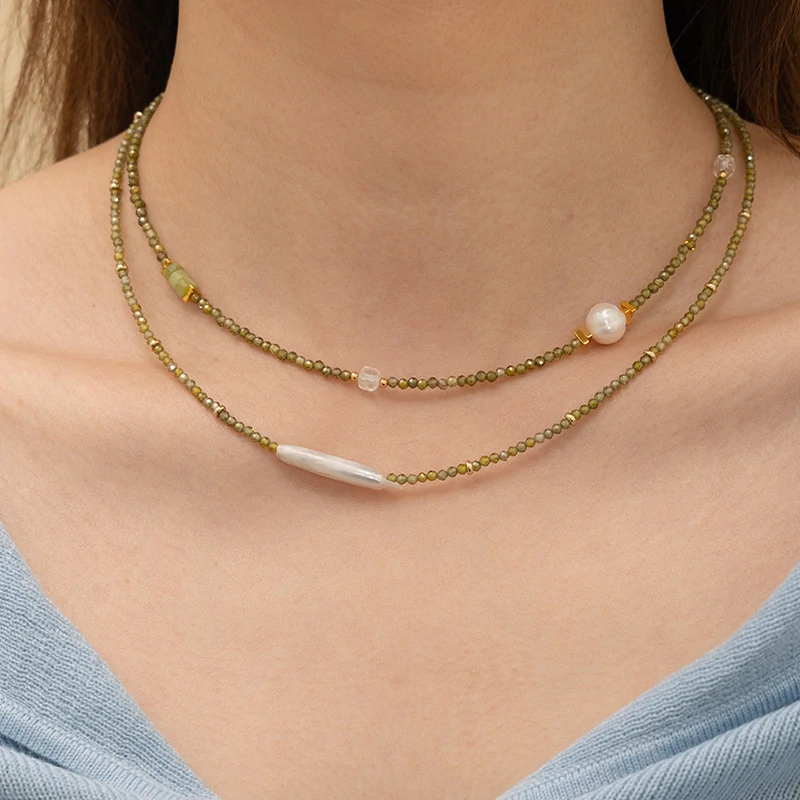 Woman wearing LIVKE pearl and green beaded necklace with silk blouse, showcasing minimalist jewelry for work and evening events