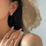 Architect wearing LIVKE gold orbital cuffs in minimalist gallery space, showcasing jewelry as wearable art