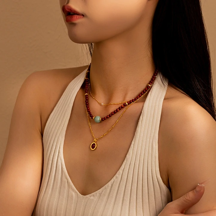 LIVKE’s 18K gold-plated red agate necklace layered with delicate chains on a linen backdrop, styled for boho-chic elegance