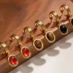 Celestial Tiger Eye Drop Earrings 7 Layered 18K gold-plated tiger eye earrings with red/black/brown stone pendants on terrazzo backdrop, styled with leather cord necklaces