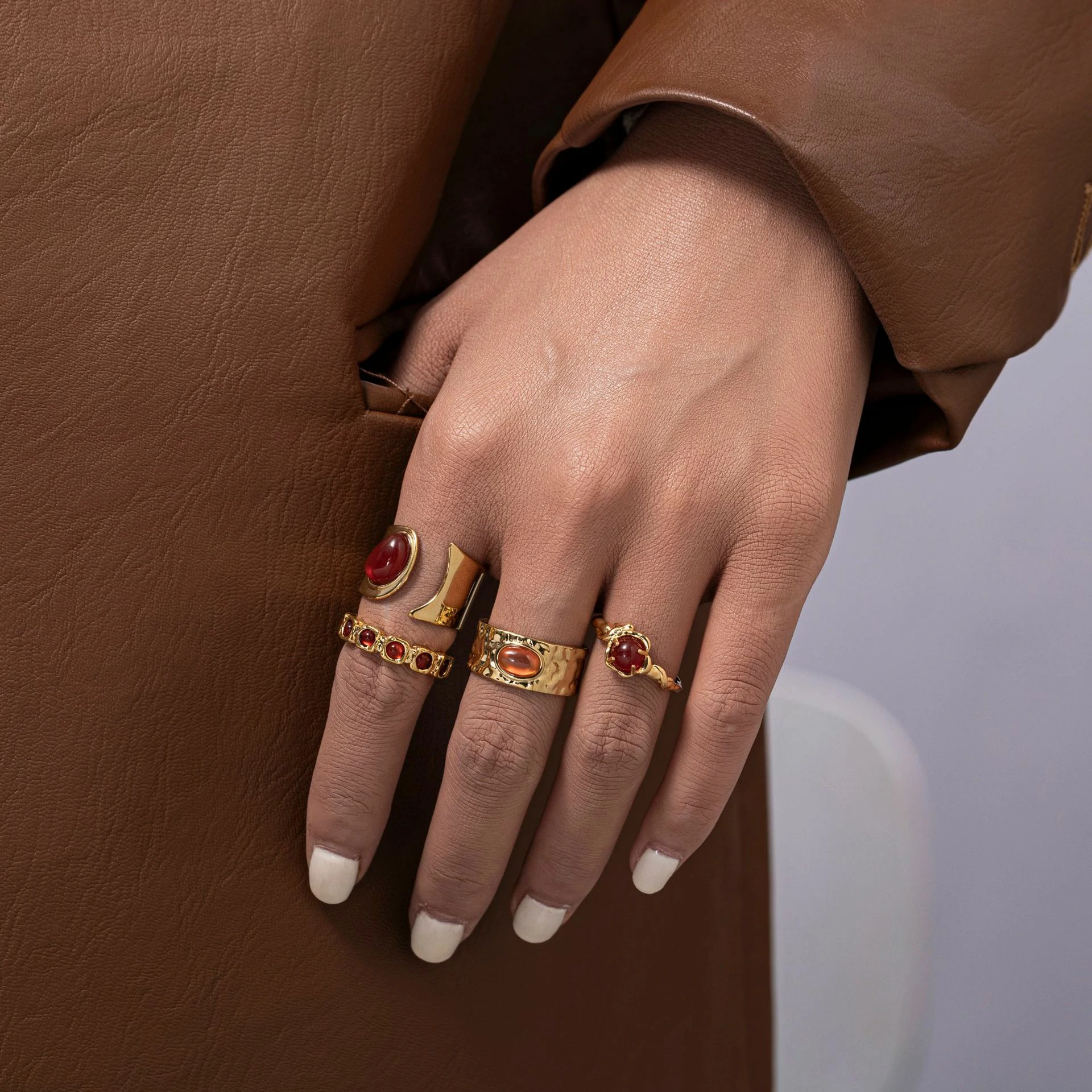 Hand wearing LIVKE red agate titanium ring with textured gold band in boardroom setting, showcasing power jewelry for professionals
