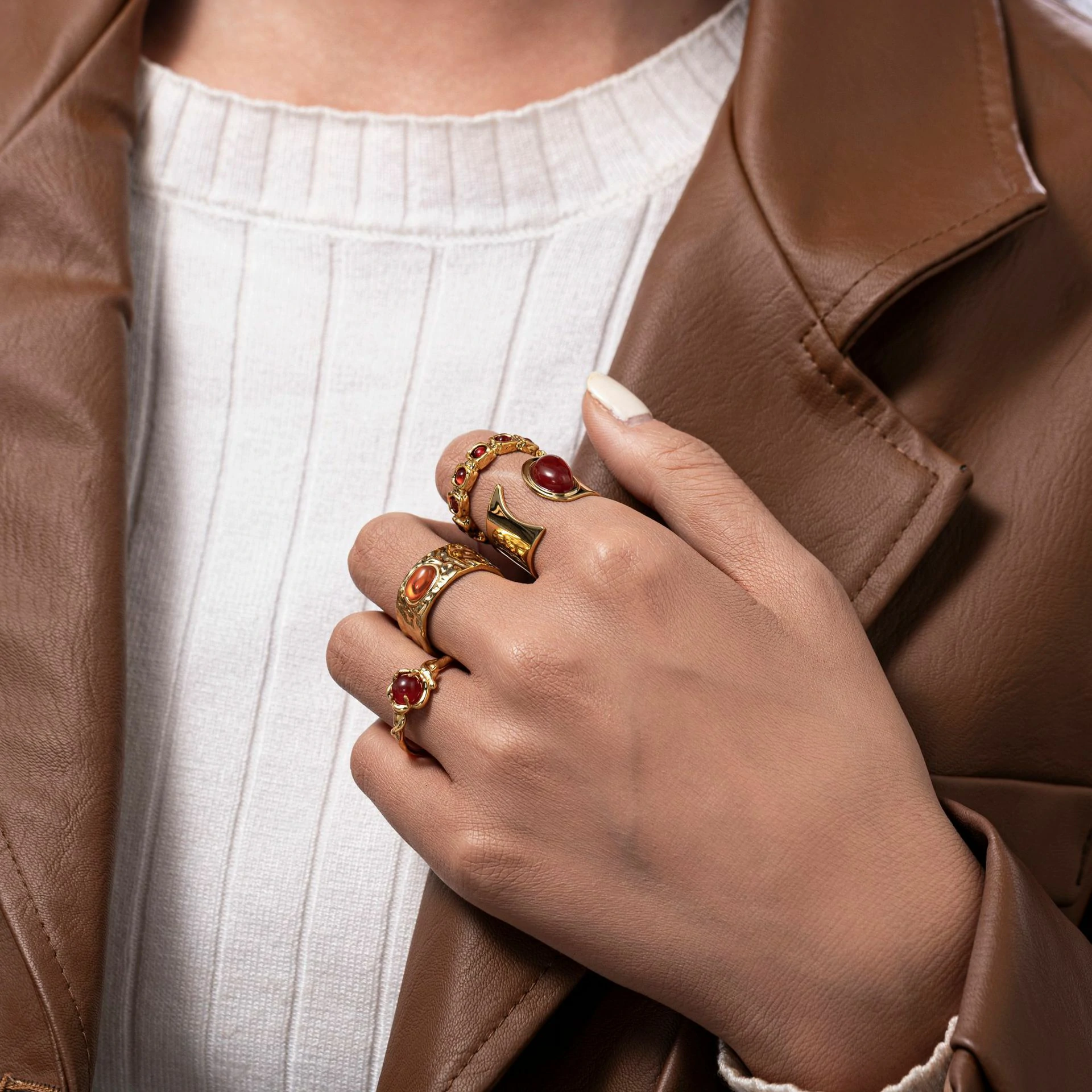 Hand wearing LIVKE red agate titanium ring with textured gold band in boardroom setting, showcasing power jewelry for professionals