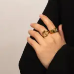 Vintage Love Signet Ring 2 Woman wearing LIVKE gold love signet ring while holding cappuccino in Parisian café, showcasing stackable jewelry styling