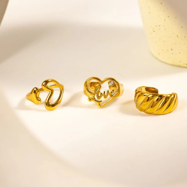 Woman wearing LIVKE gold love signet ring while holding cappuccino in Parisian café, showcasing stackable jewelry styling