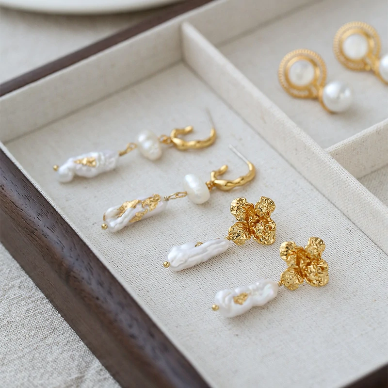 Woman wearing LIVKE vintage pearl earrings with a black evening dress, golden flowers and baroque pearls reflect the vintage luster under candlelight