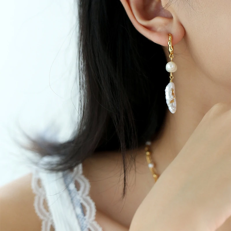 Woman wearing LIVKE vintage pearl earrings with a black evening dress, golden flowers and baroque pearls reflect the vintage luster under candlelight