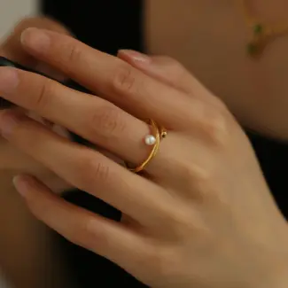 Hand model adjusting open wave ring with pearl under golden hour sunlight