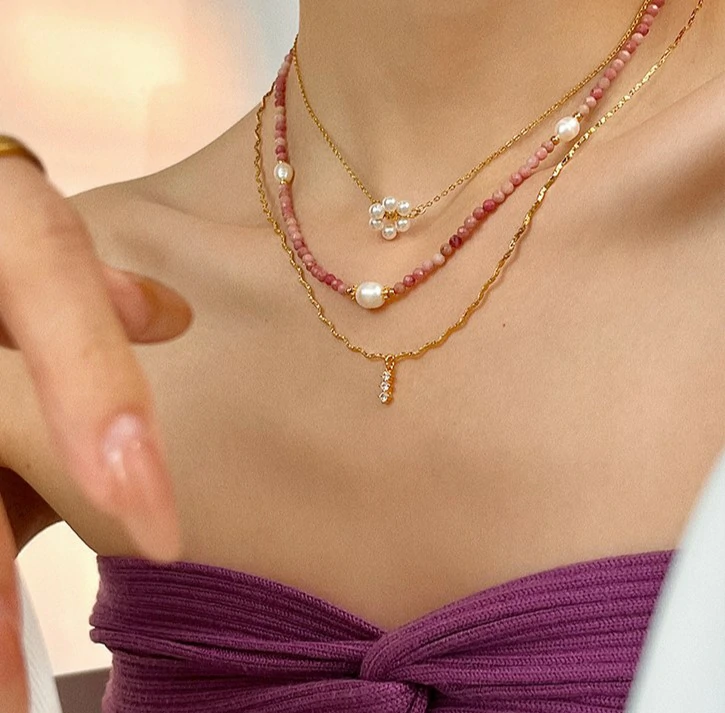 Close-up of LIVKE Y2K mystic necklace with raw amethyst, pearl, and cubic zirconia on model with holographic eyeshadow, showcasing edgy boho jewelry